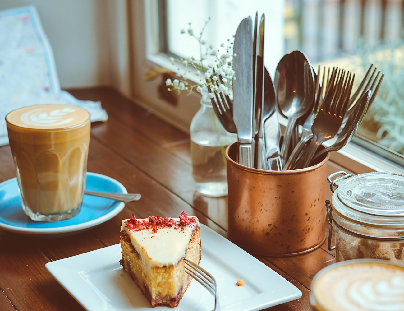 A slice of cake and a flat white by the window